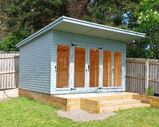 Pale blue pent summer house on a raised sleeper deck