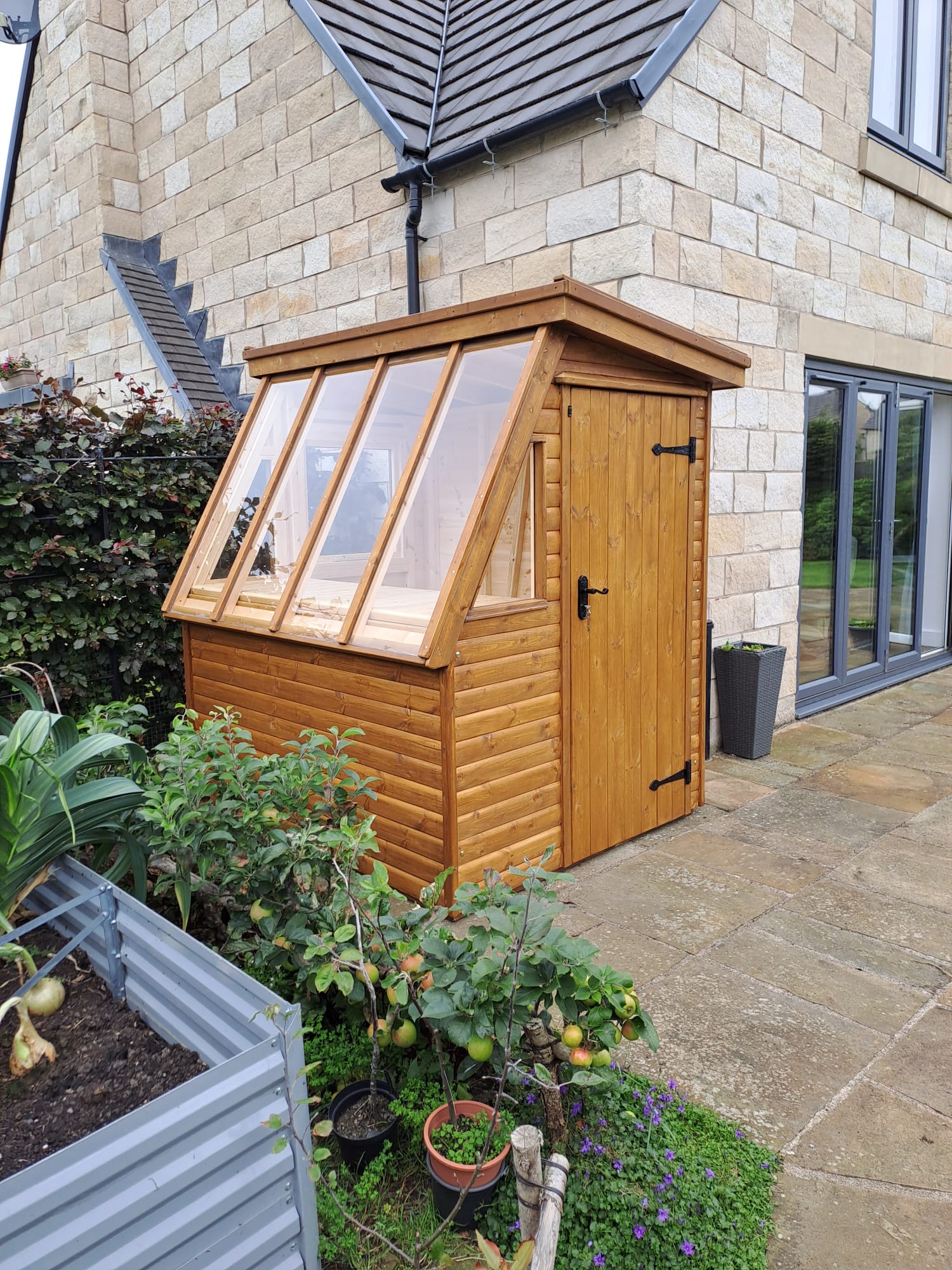 Potting shed with glazed roof beside a stone house