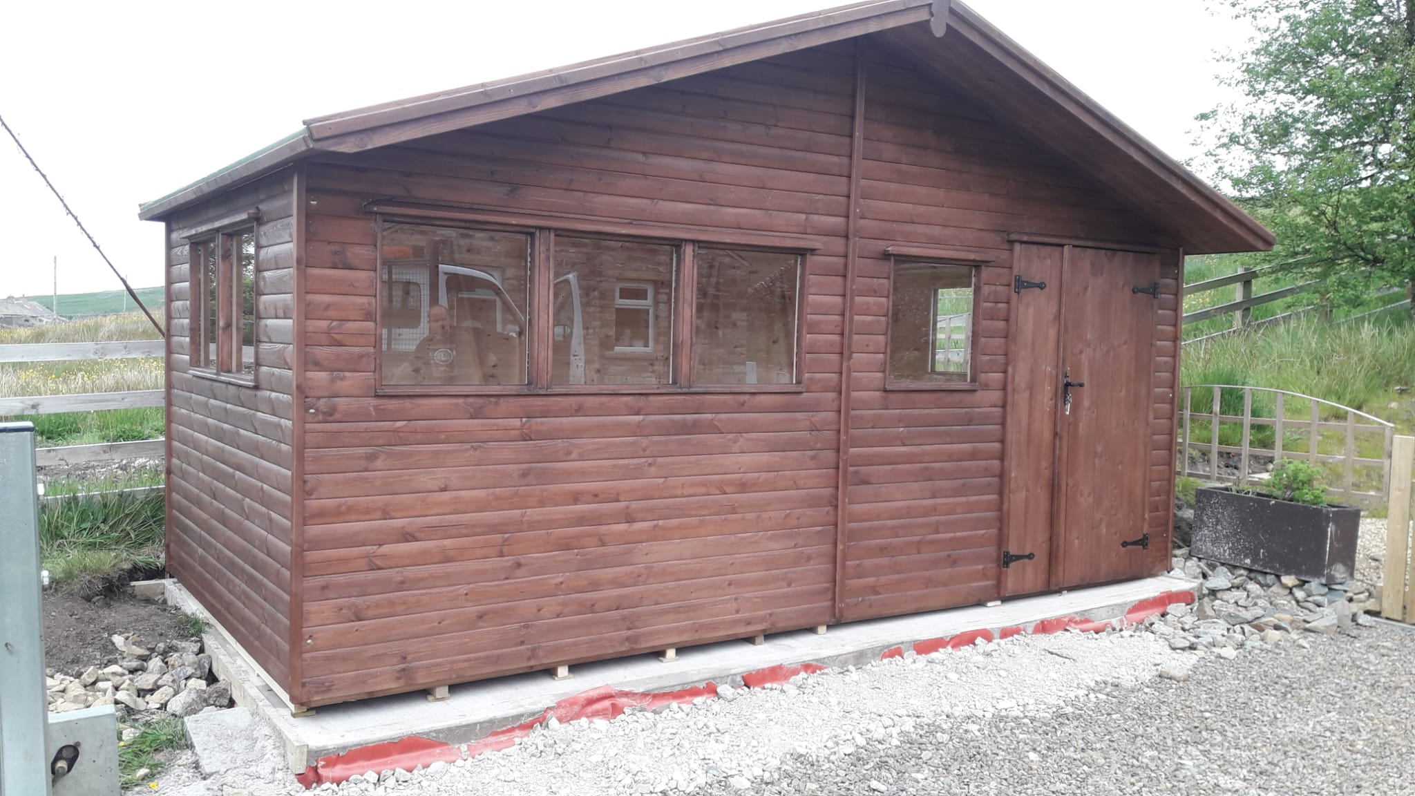 Large dark stained workshop shed with a row of windows