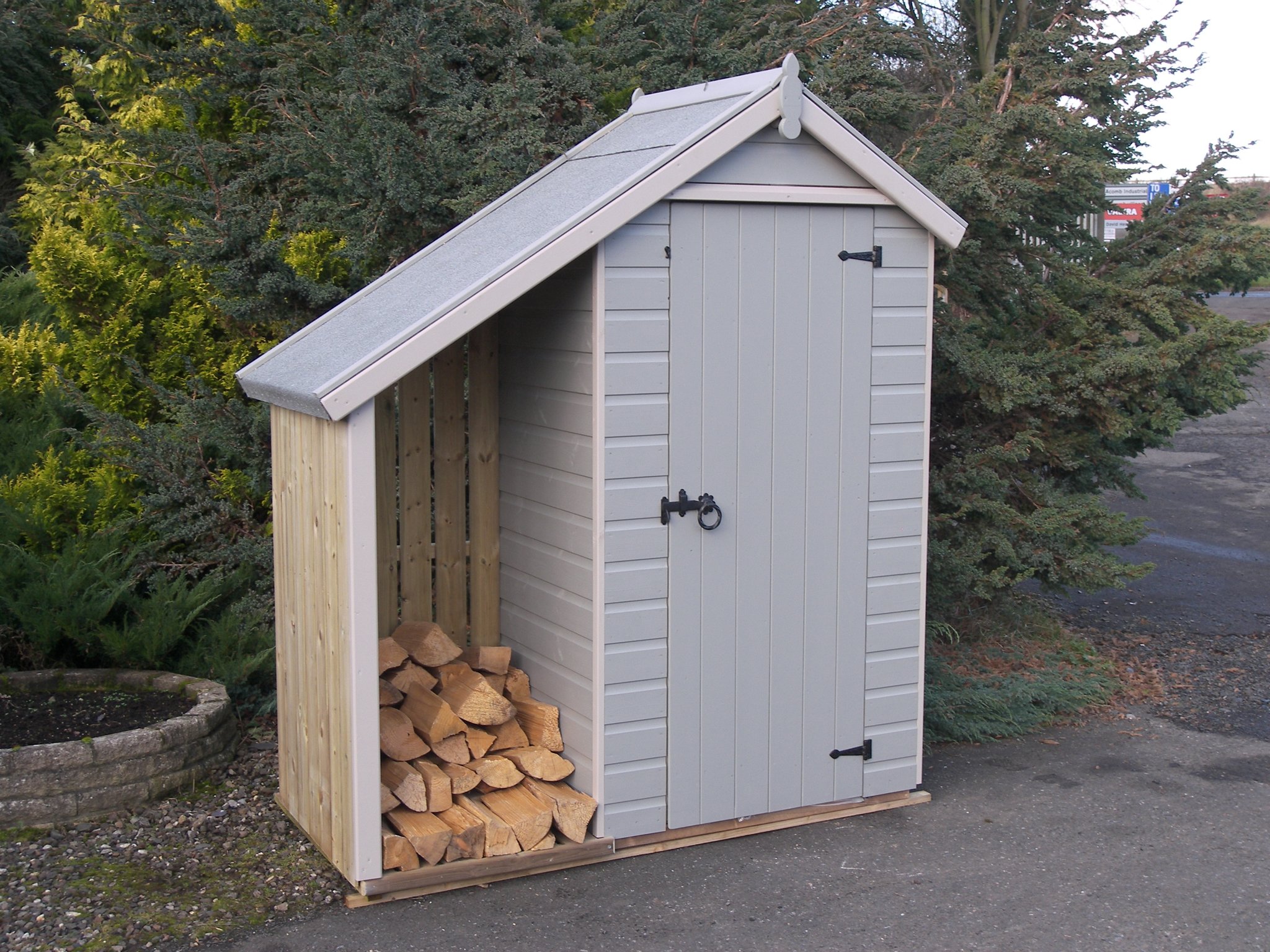 Grey combination store with a log bay full of logs