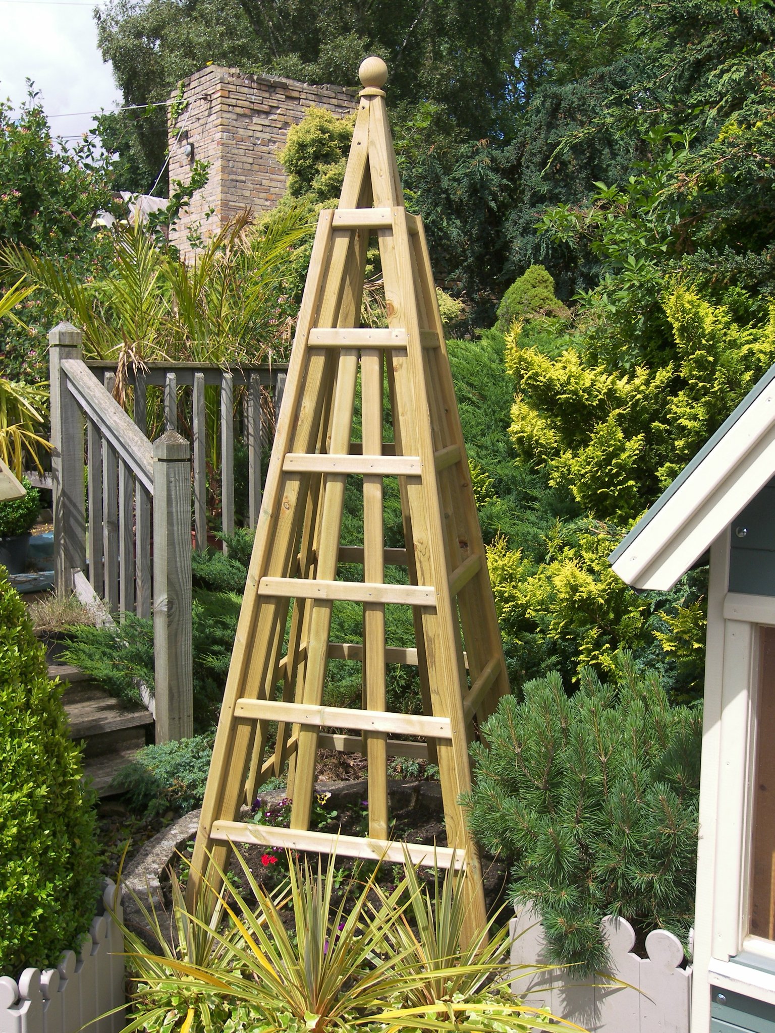 Tall timber garden obelisk among shrubs