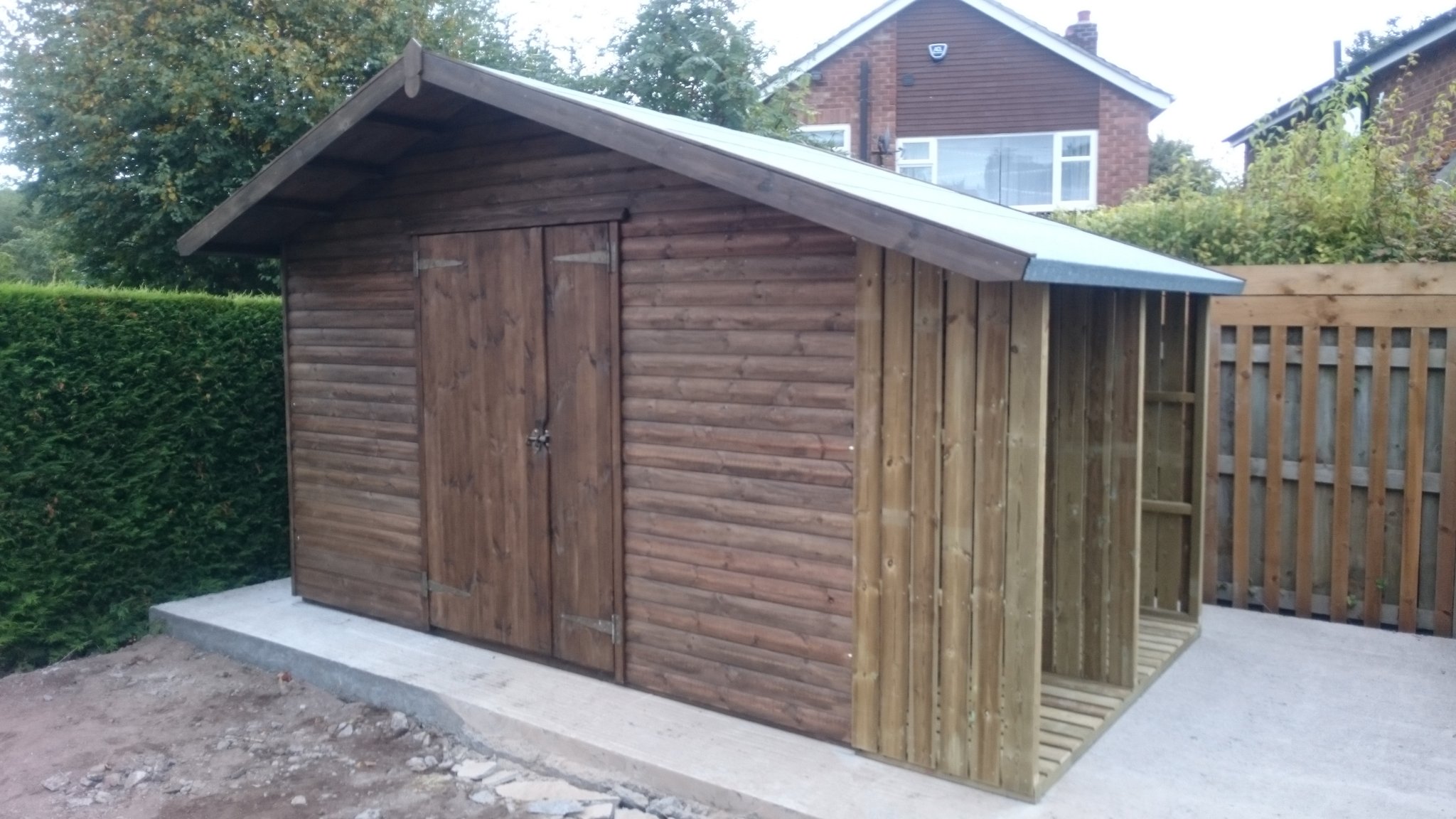 Stained shed with an open log store on the end