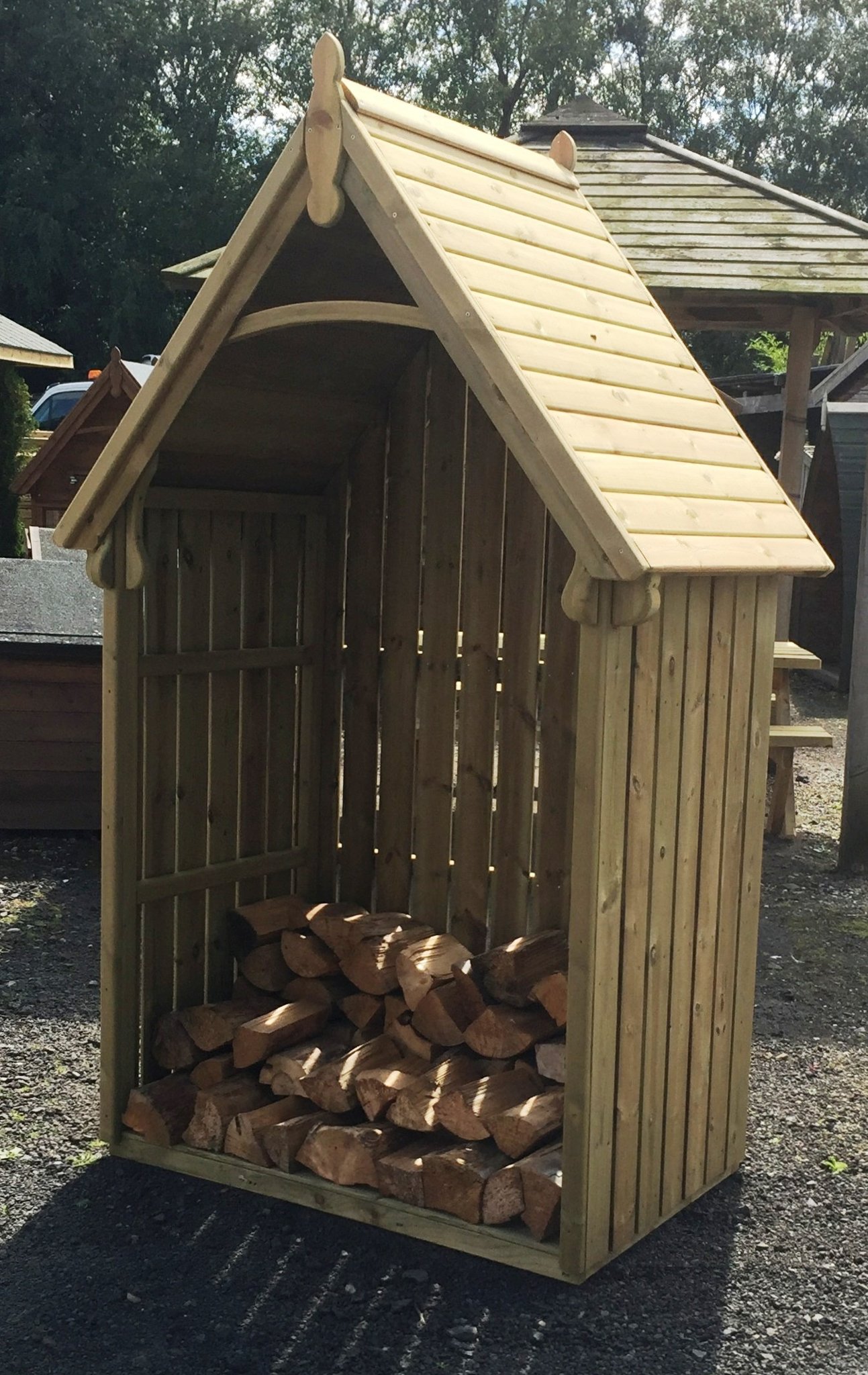 Fellside log store with a pitched roof and logs stacked inside
