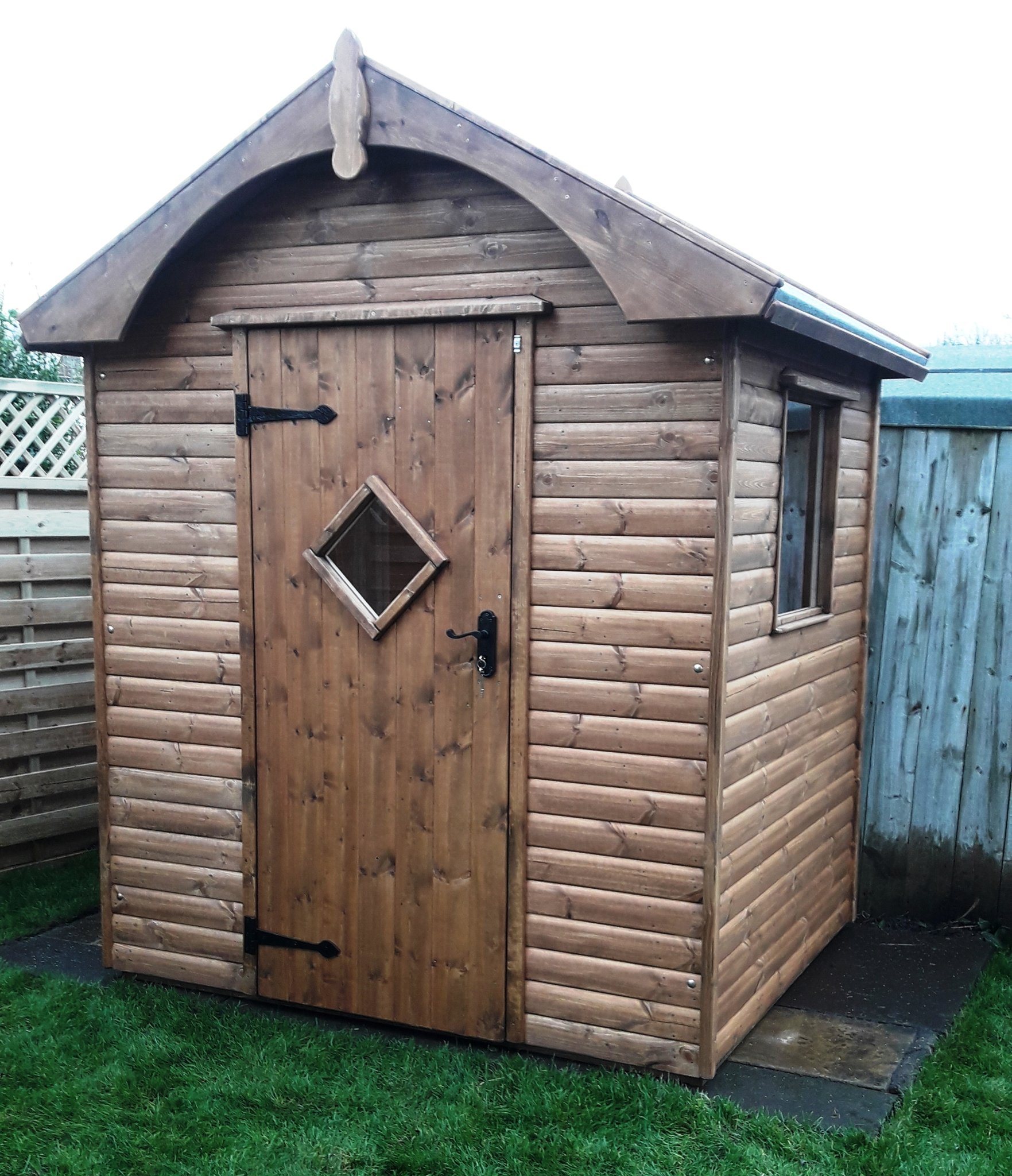 Stained shed with an arched bargeboard, finial and diamond window