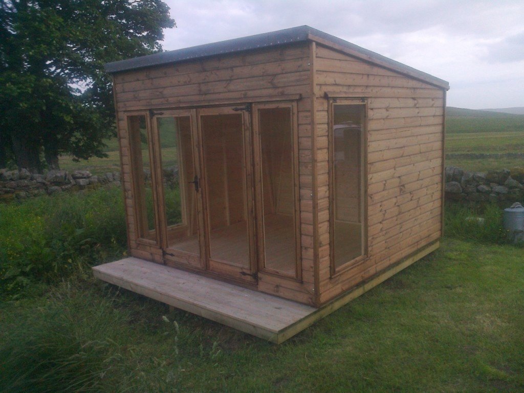 Stained pent summer house with a deck in open countryside