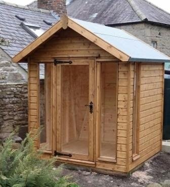 Stained apex summer house beside a stone building