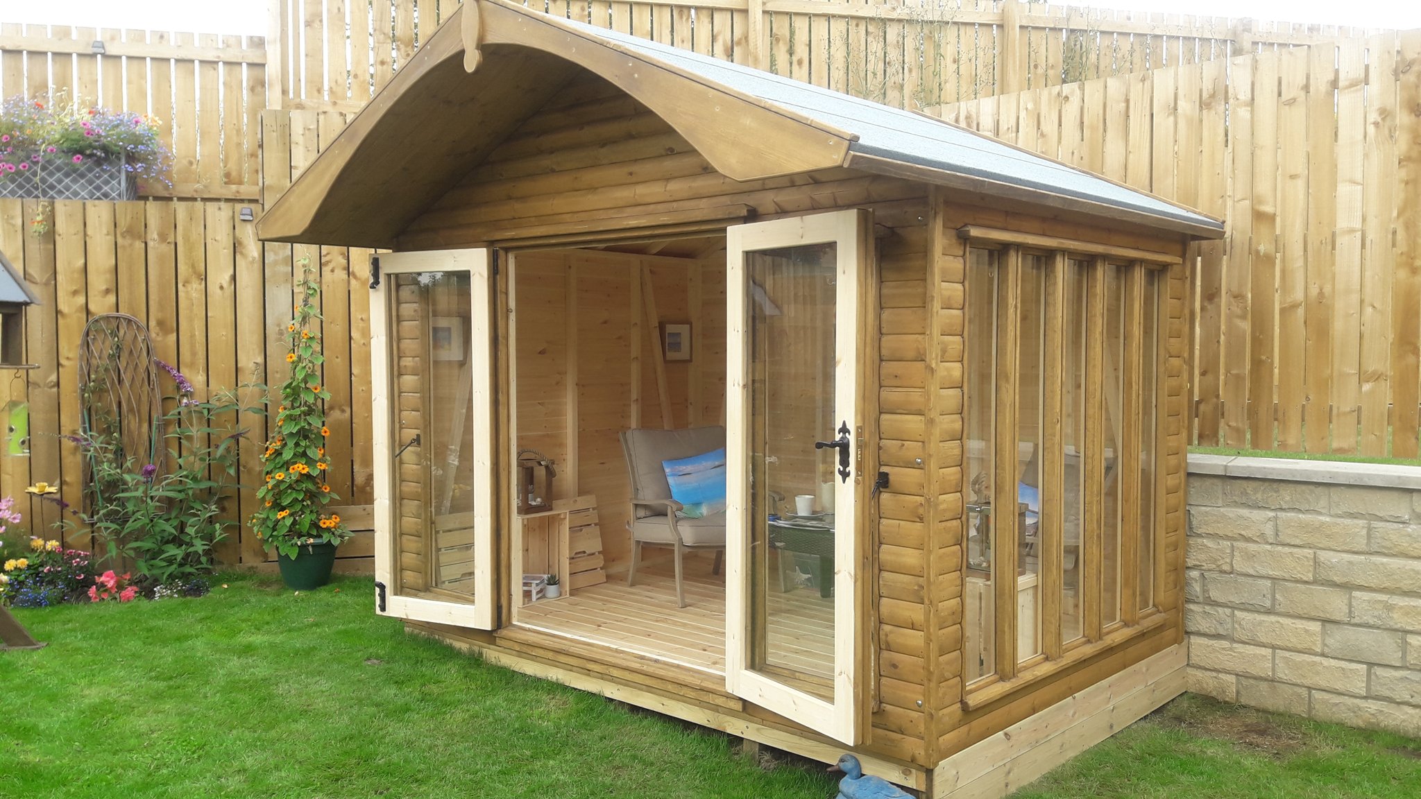 Summer house with an arched roof and glazed doors open onto a lawn